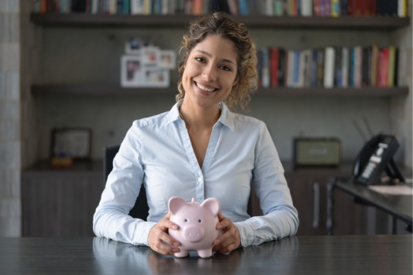 Woman smiling looking at camera with a piggybank in hand